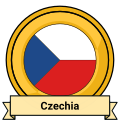 A stylized metalic badge. It appears to be made of gold and features the flag of Czechia. A ribbon bearing the country's name sits on the bottom.
